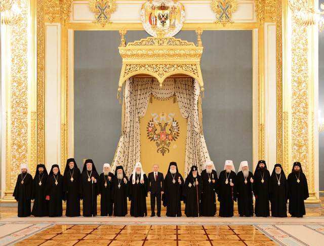 Putin standing under the Double Headed Eagle with members of the Russian Orthodox Church